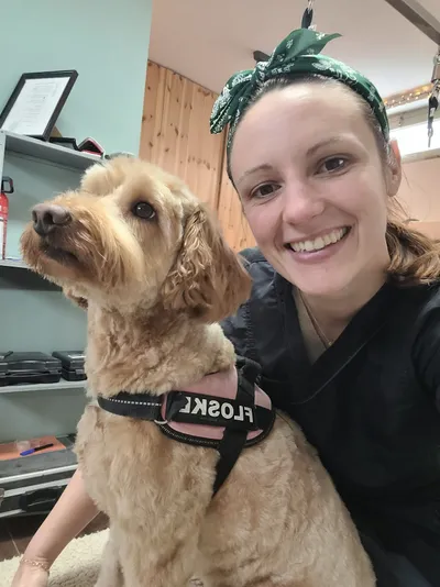Cynthia lacht in de camera met Floske, een labradoodle, naast zich